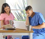 Woman looking at the bill. Man looking at the laptop.