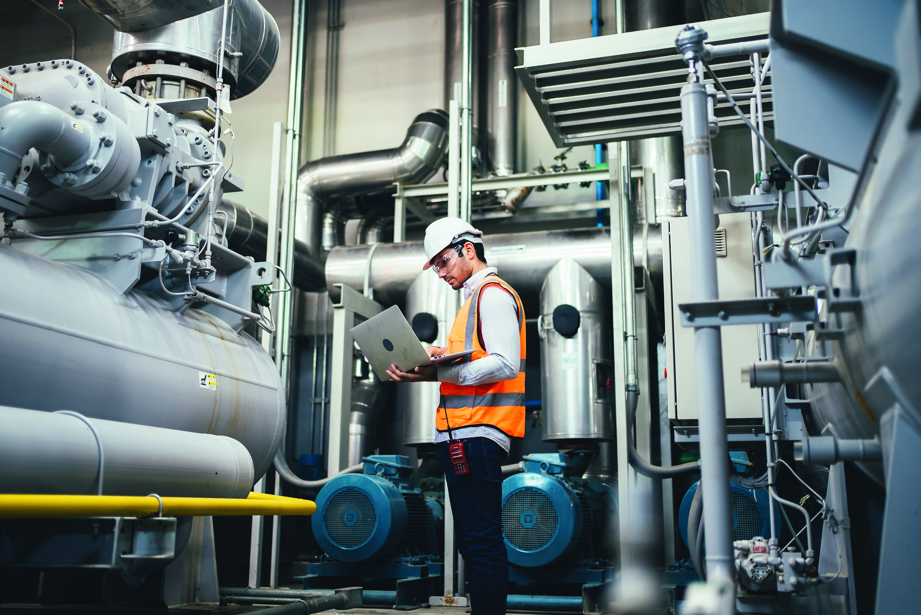 man in hard hat inspecting pumps